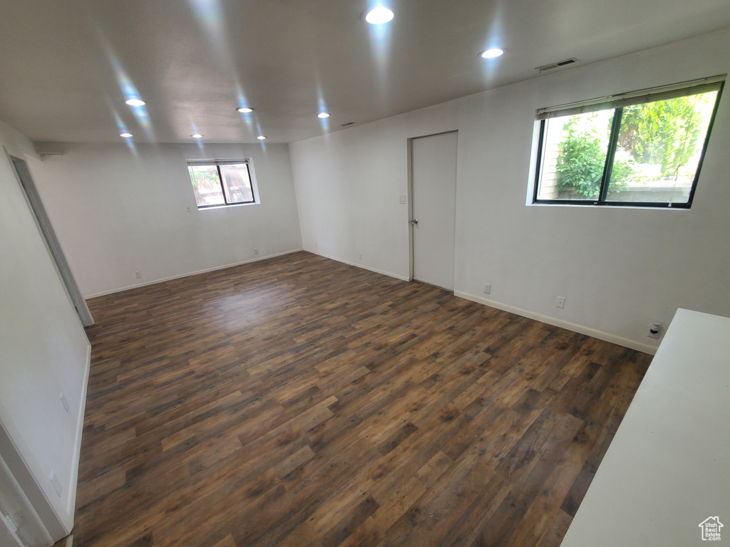 Empty room with dark wood-style flooring, recessed lighting, and baseboards