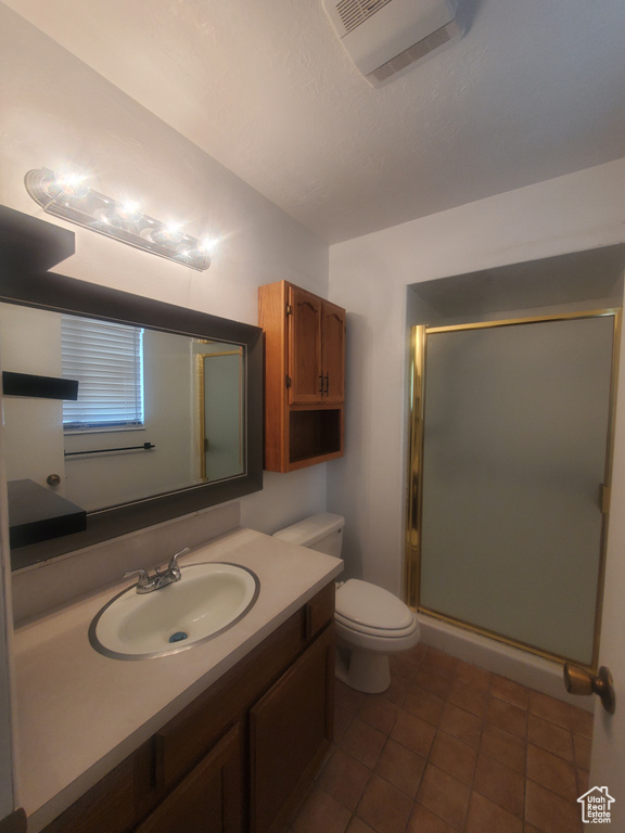 Full bath featuring vanity, toilet, a stall shower, and tile patterned flooring