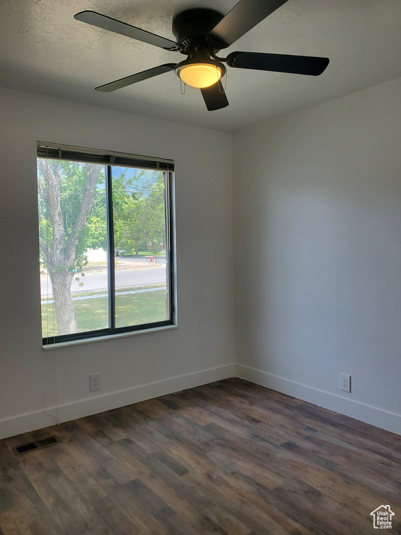Unfurnished room with dark wood finished floors, ceiling fan, and baseboards