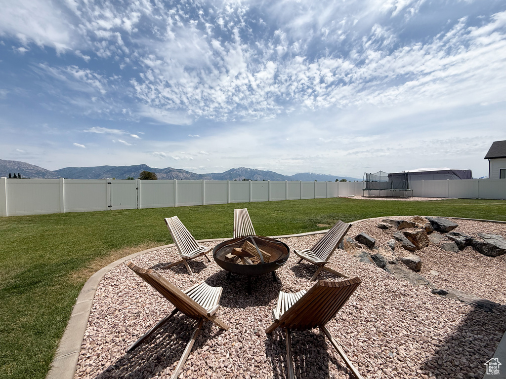View of yard with a trampoline, an outdoor fire pit, and a mountain view