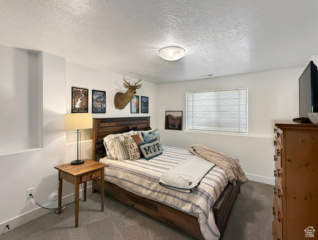 Carpeted bedroom featuring a textured ceiling and baseboards