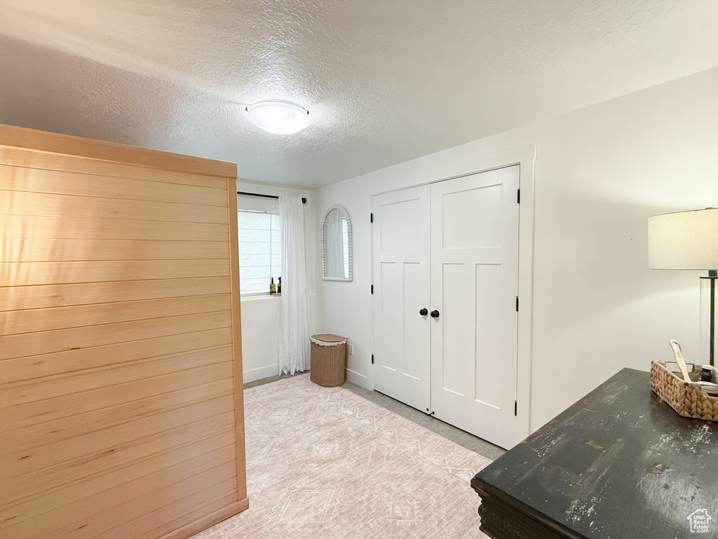 Bedroom featuring a textured ceiling, light colored carpet, and a closet