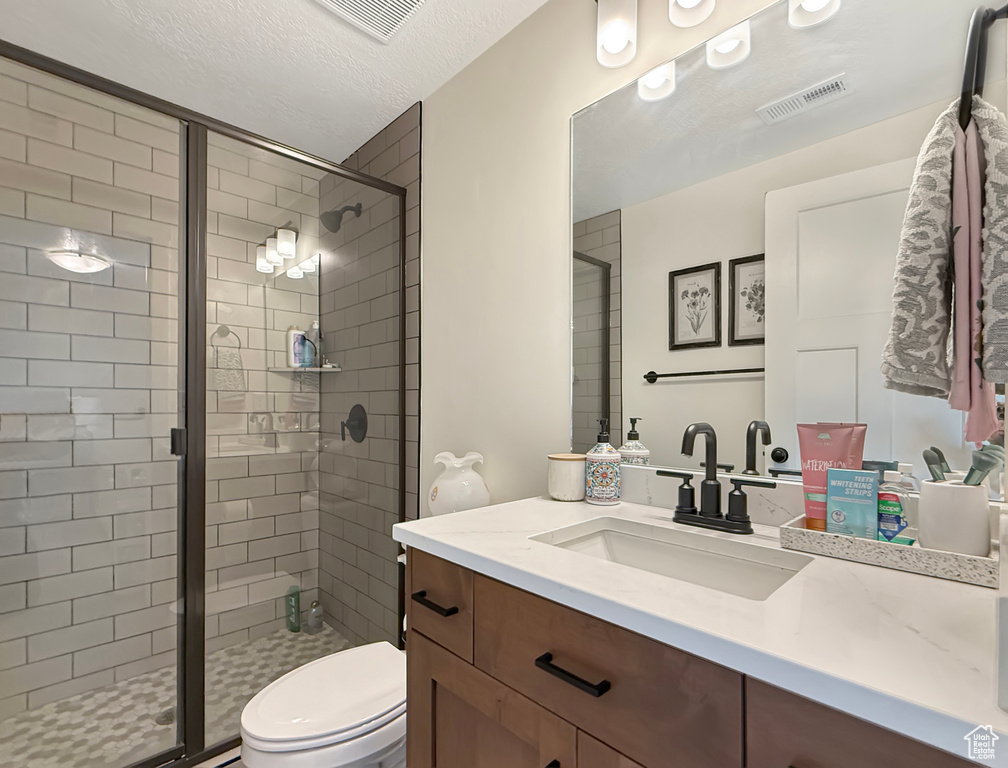 Bathroom with vanity, toilet, and a stall shower