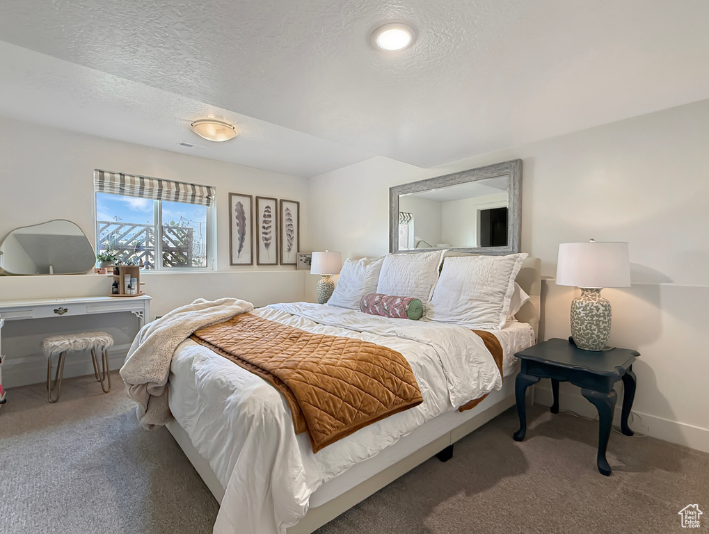 Bedroom with carpet floors, baseboards, a textured ceiling, and an office area
