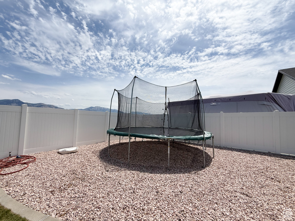 Fenced backyard with a trampoline and a mountain view