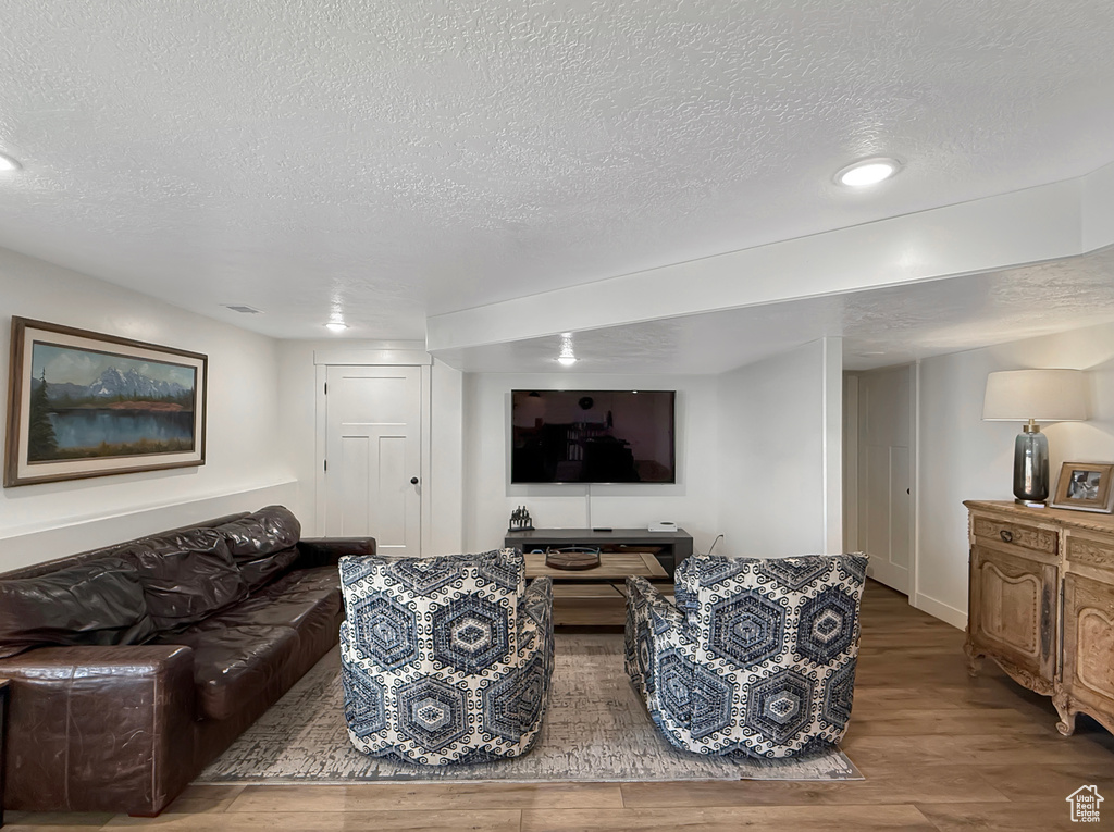 Living area with a textured ceiling, wood finished floors, recessed lighting, and baseboards