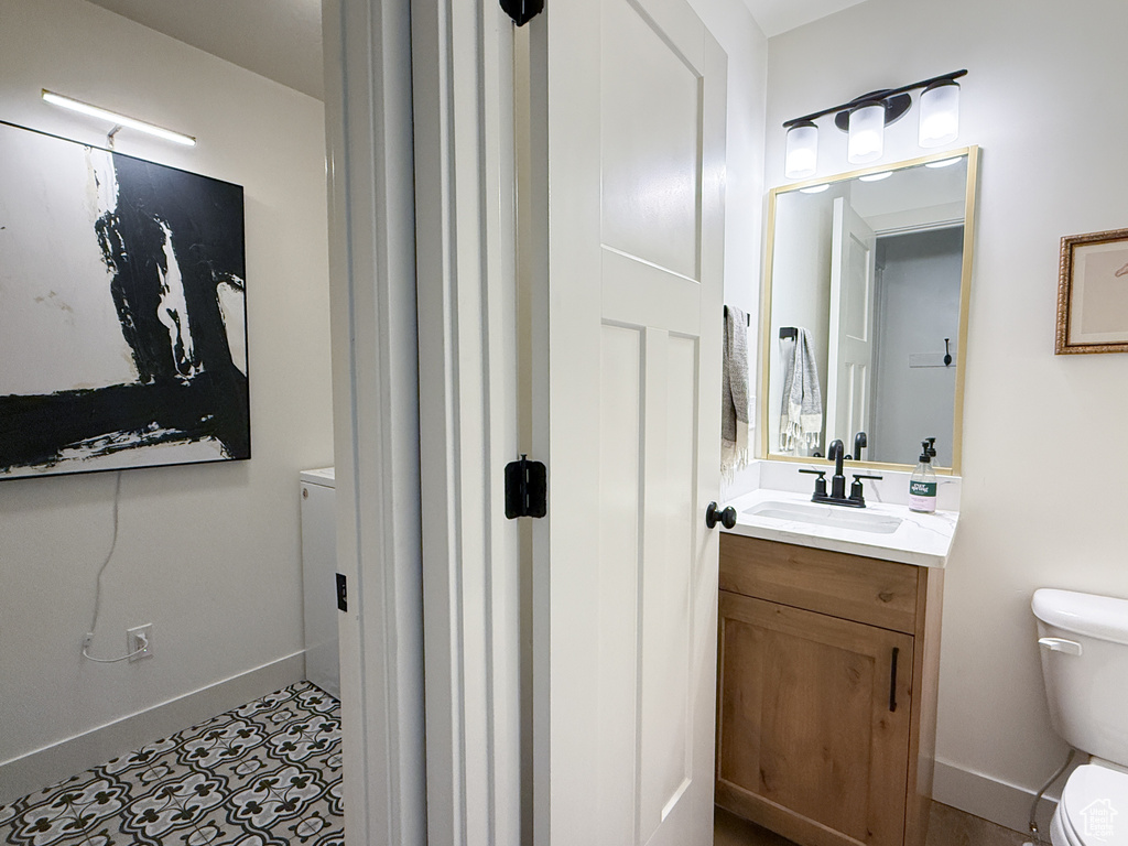 Half bathroom featuring toilet, vanity, and baseboards