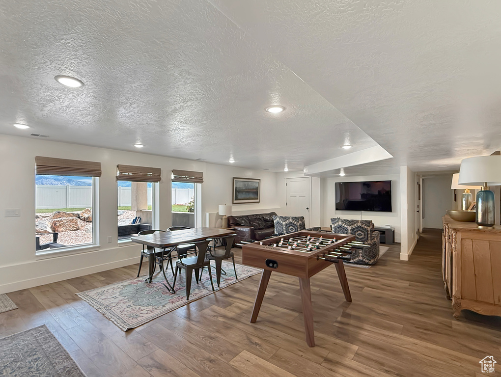 Recreation room with a textured ceiling, wood finished floors, baseboards, and recessed lighting
