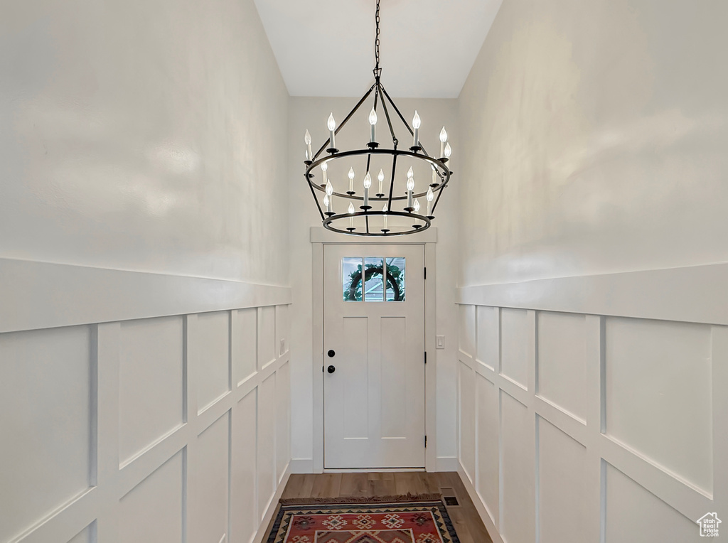 Doorway to outside featuring a decorative wall, a chandelier, and dark wood-style flooring