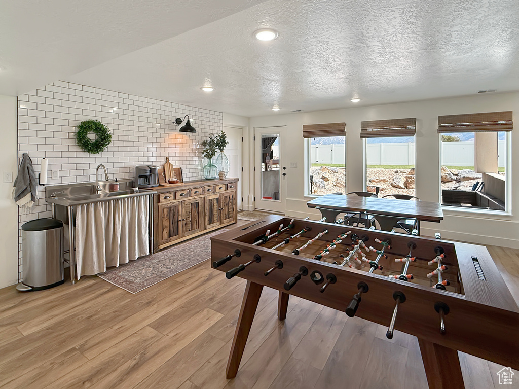Game room featuring light wood-type flooring, a textured ceiling, and recessed lighting