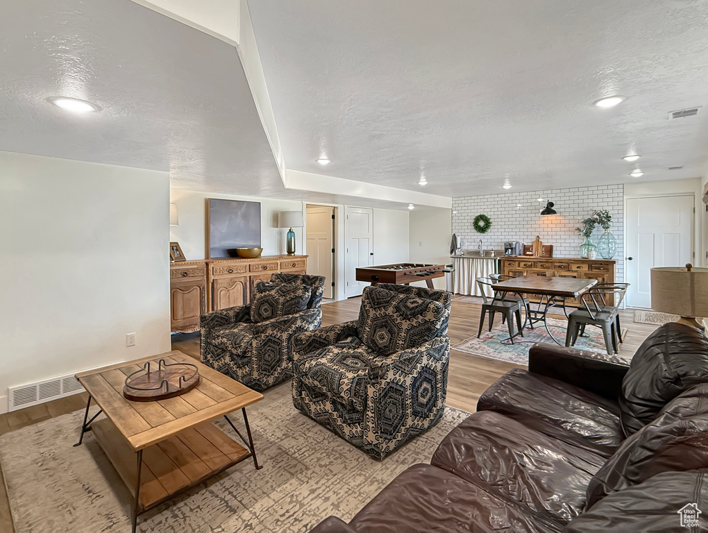 Living room featuring light wood finished floors, a textured ceiling, and recessed lighting