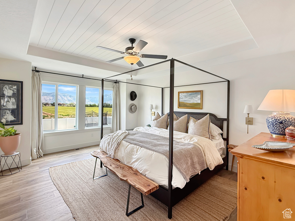 Bedroom featuring a tray ceiling, light wood-style flooring, wood ceiling, and ceiling fan