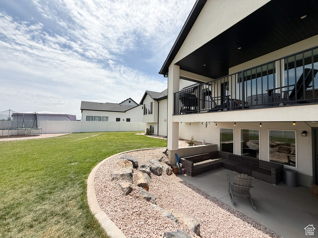 View of yard featuring a trampoline, a patio, a balcony, and an outdoor living space