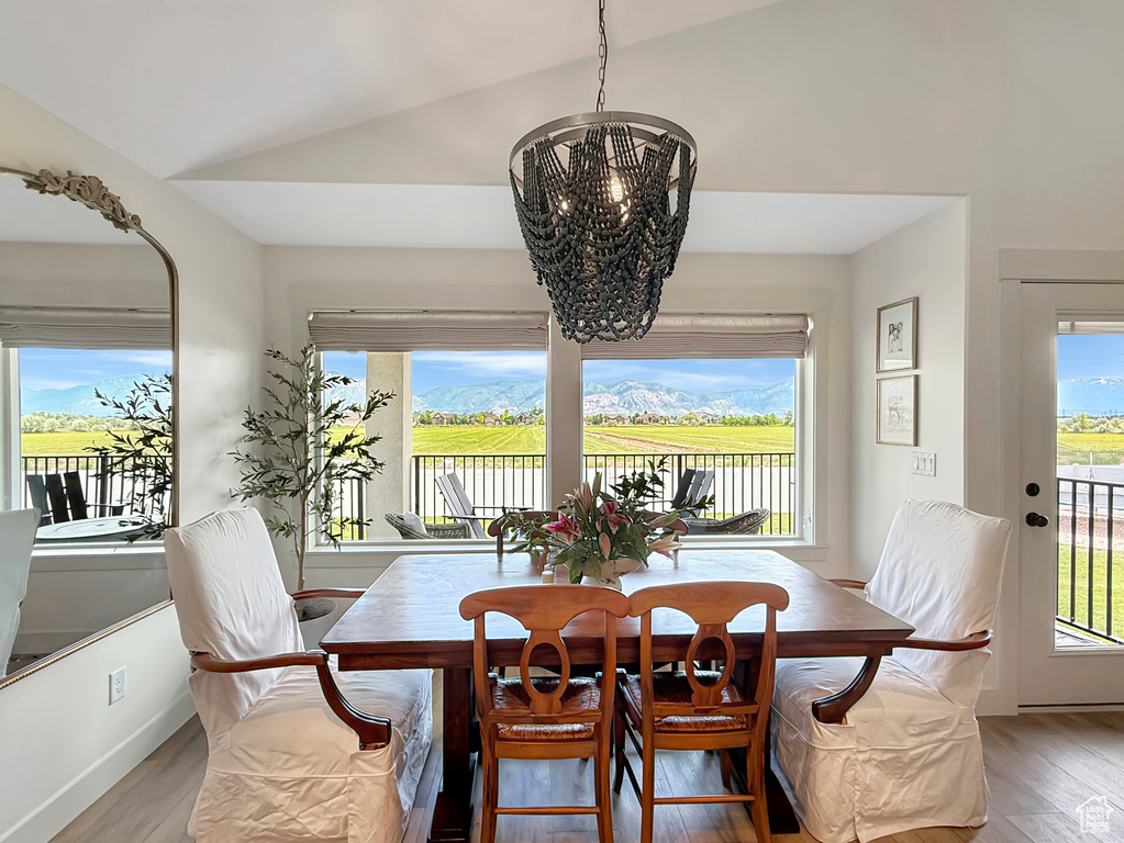 Dining room with a chandelier, light wood finished floors, and lofted ceiling