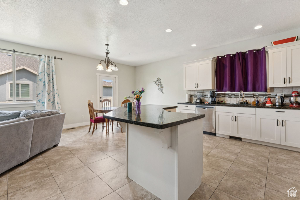 Kitchen with stainless steel dishwasher, a sink, decorative backsplash, a chandelier, and a center island