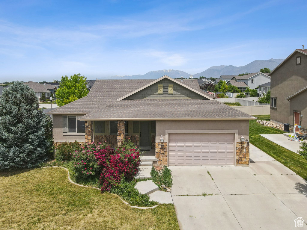 View of front of property with a shingled roof, stone siding, and concrete driveway
