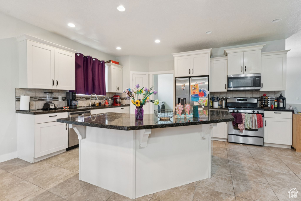 Kitchen with appliances with stainless steel finishes, decorative backsplash, white cabinets, and recessed lighting