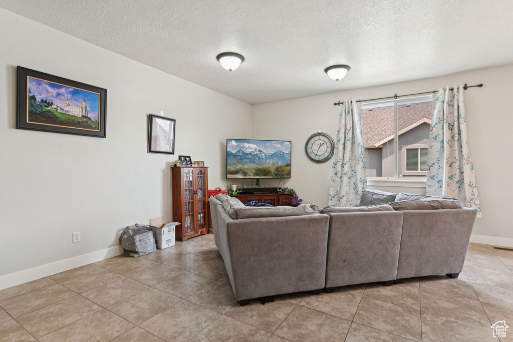 Living room featuring baseboards, light tile patterned floors, and a textured ceiling