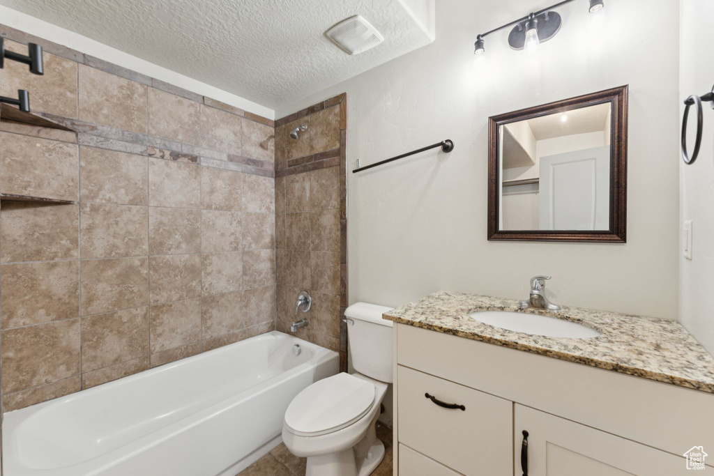 Bathroom featuring toilet, a textured ceiling, vanity, and bathtub / shower combination