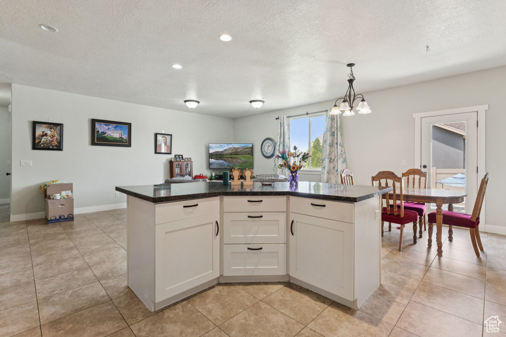 Kitchen featuring a chandelier, white cabinetry, a textured ceiling, dark countertops, and baseboards