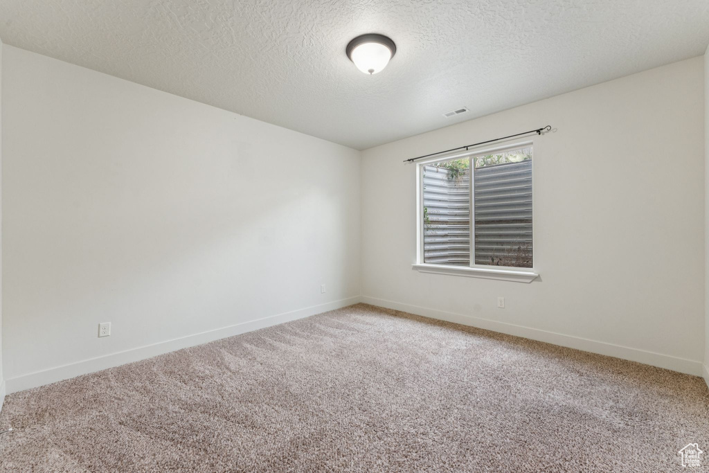 Unfurnished room featuring carpet floors, baseboards, and a textured ceiling