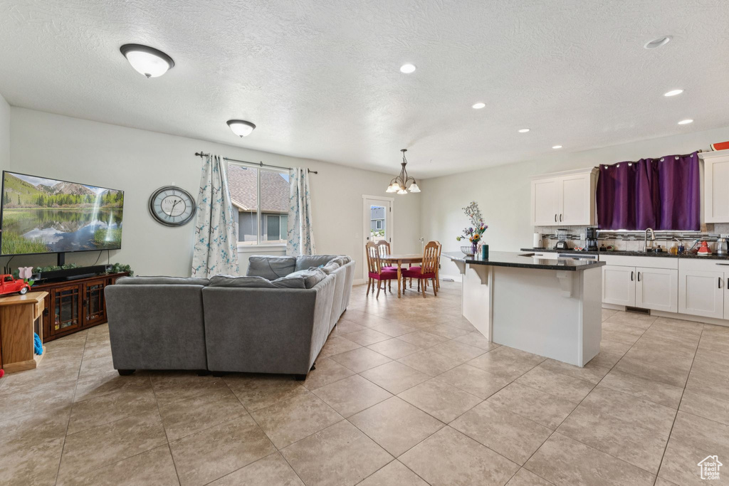 Living room featuring a chandelier, a textured ceiling, light tile patterned floors, and recessed lighting