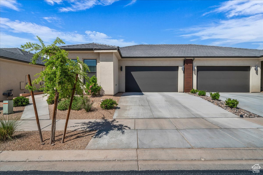 View of front of home featuring a tiled roof, an attached garage, driveway, and stucco siding