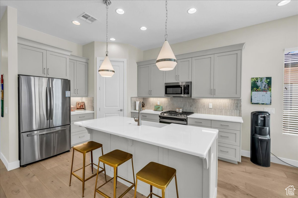Kitchen featuring appliances with stainless steel finishes, gray cabinetry, light wood-style floors, backsplash, and recessed lighting