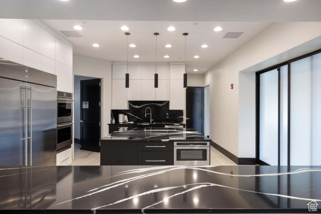 Kitchen featuring modern cabinets, stainless steel appliances, white cabinetry, and recessed lighting