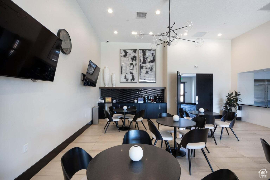 Dining room with a towering ceiling, a chandelier, light tile patterned floors, and recessed lighting