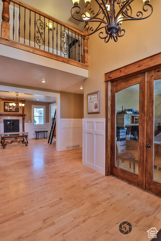 Entryway with a chandelier, wood finished floors, wainscoting, a towering ceiling, and french doors