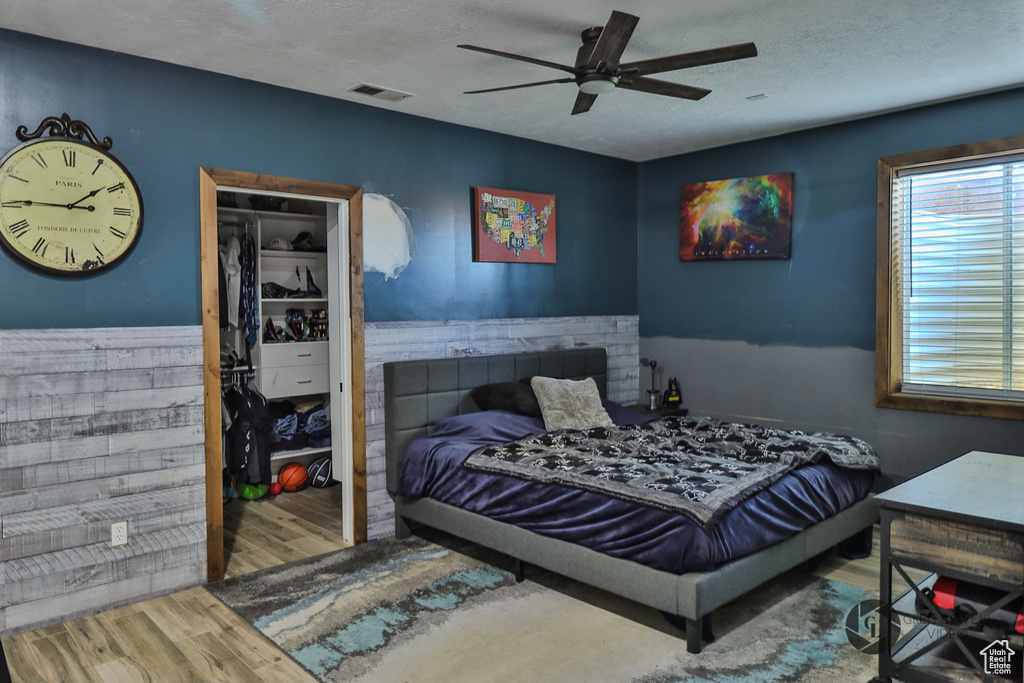 Bedroom with wood finished floors, a textured ceiling, and ceiling fan