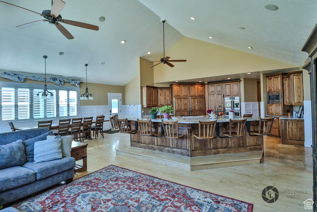 Living area featuring ceiling fan, high vaulted ceiling, light wood-style flooring, and recessed lighting