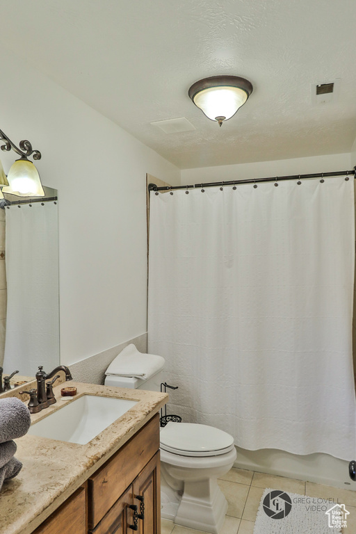 Full bathroom featuring toilet, vanity, and tile patterned flooring