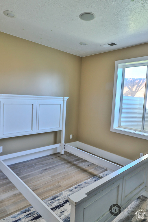 Unfurnished bedroom featuring light wood-style floors and a textured ceiling