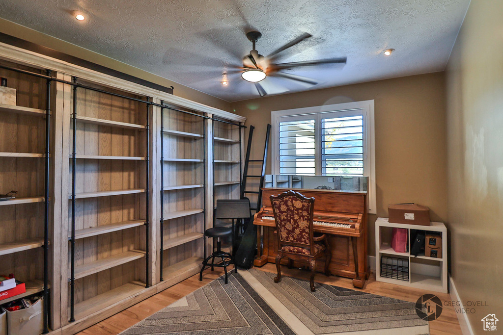 Home office with ceiling fan, wood finished floors, and a textured ceiling