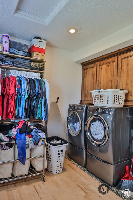 Laundry room with separate washer and dryer, wood finished floors, cabinet space, and recessed lighting
