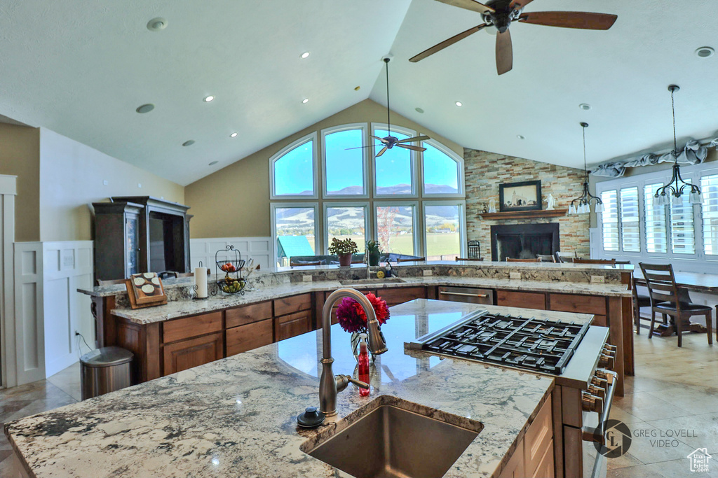 Kitchen with appliances with stainless steel finishes, ceiling fan, a sink, brown cabinets, and high vaulted ceiling