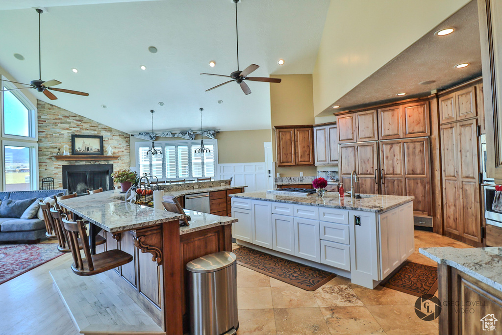 Kitchen featuring a ceiling fan, a large island, high vaulted ceiling, open floor plan, and a large fireplace