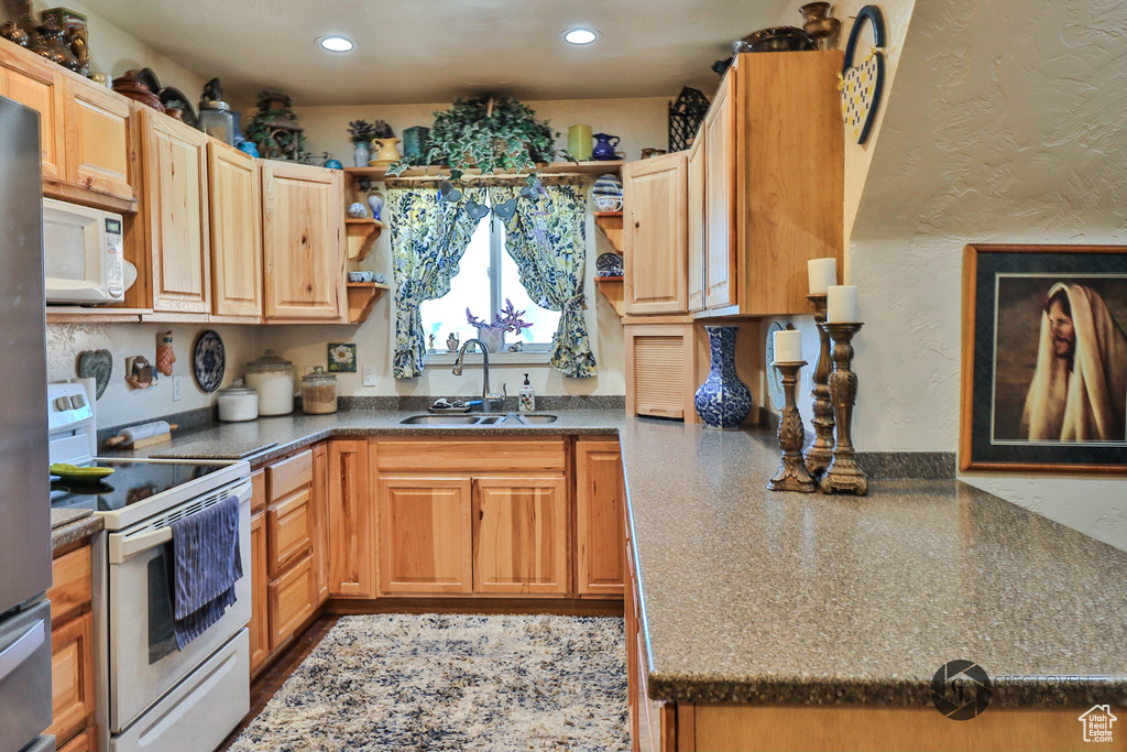 Kitchen with white appliances, a sink, open shelves, dark countertops, and recessed lighting
