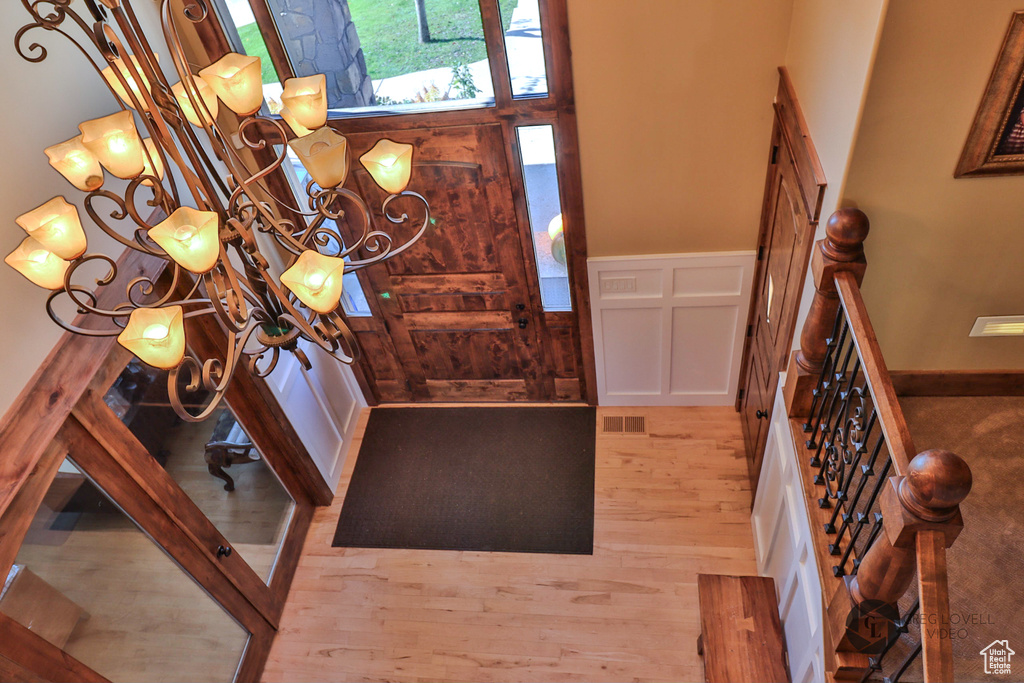 Foyer featuring wood finished floors, a decorative wall, a wainscoted wall, and stairs