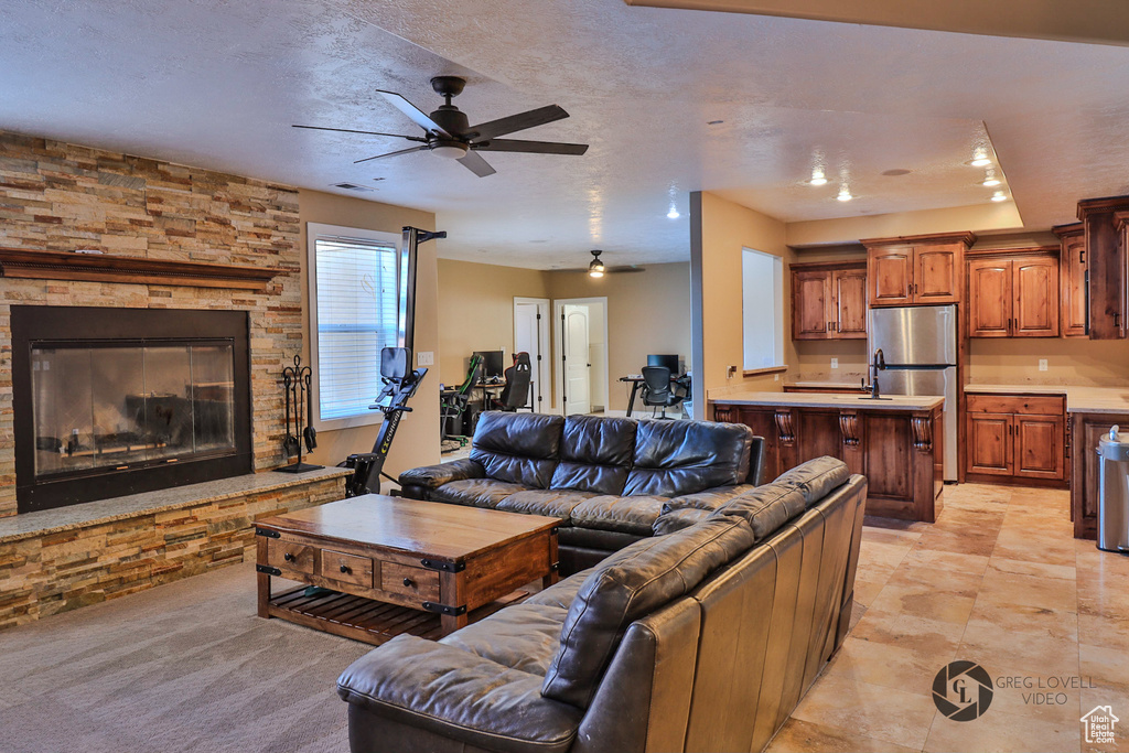 Living area with a ceiling fan and a stone fireplace