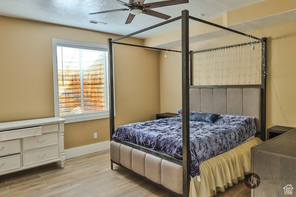 Bedroom featuring multiple windows, wood finished floors, baseboards, a textured ceiling, and ceiling fan