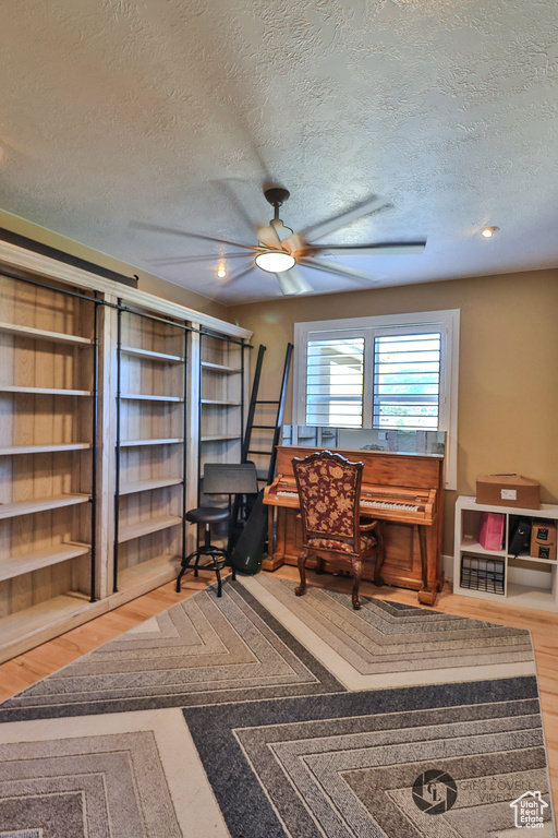 Office area with ceiling fan, a textured ceiling, and wood finished floors