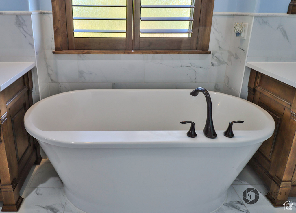 Bathroom featuring marble look tile flooring, vanity, and plenty of natural light