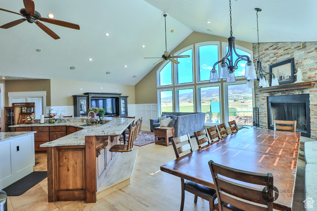 Kitchen featuring a ceiling fan, high vaulted ceiling, a sink, open floor plan, and light stone countertops