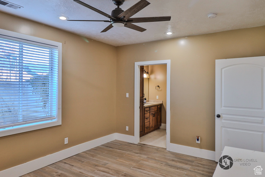 Unfurnished bedroom with baseboards, light wood-style flooring, recessed lighting, connected bathroom, and a sink