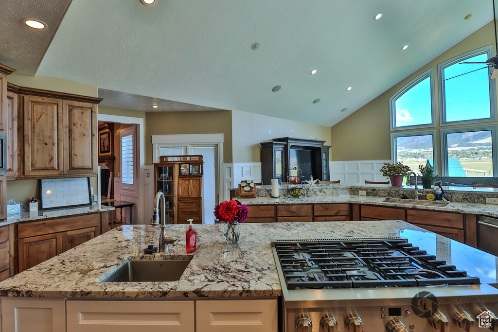 Kitchen featuring a sink, gas cooktop, brown cabinetry, recessed lighting, and high vaulted ceiling
