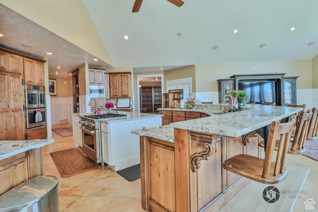 Kitchen with a sink, stainless steel appliances, a spacious island, recessed lighting, and light stone countertops
