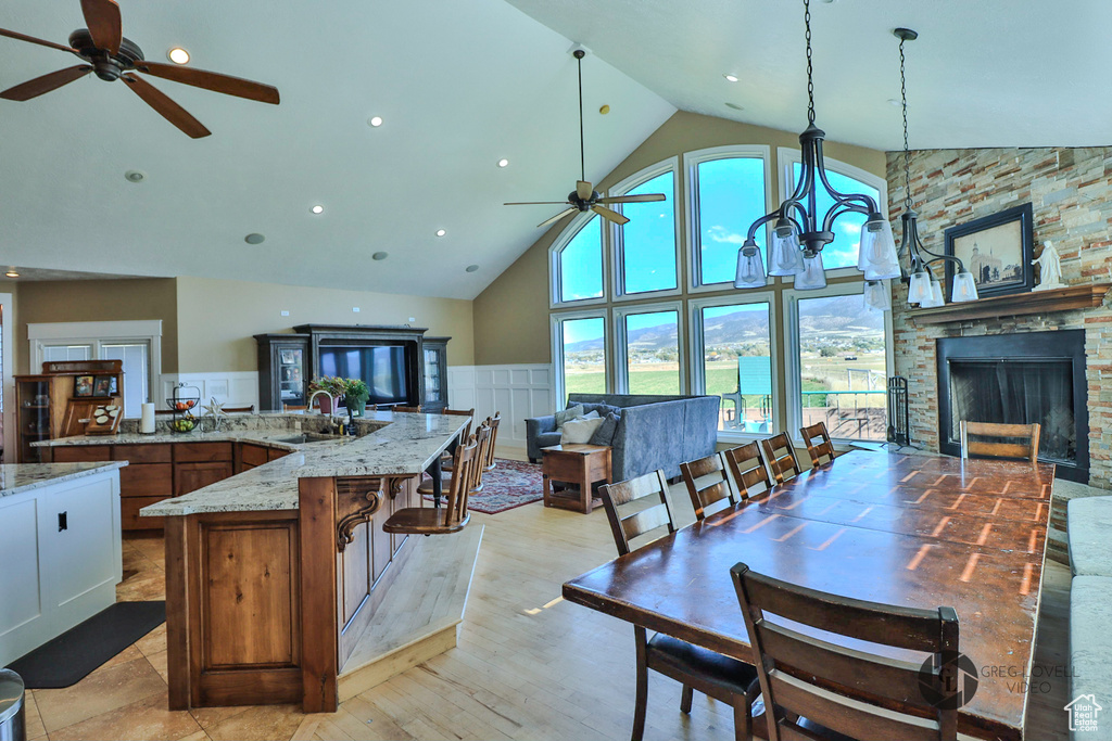 Kitchen featuring ceiling fan, high vaulted ceiling, a sink, open floor plan, and light stone counters